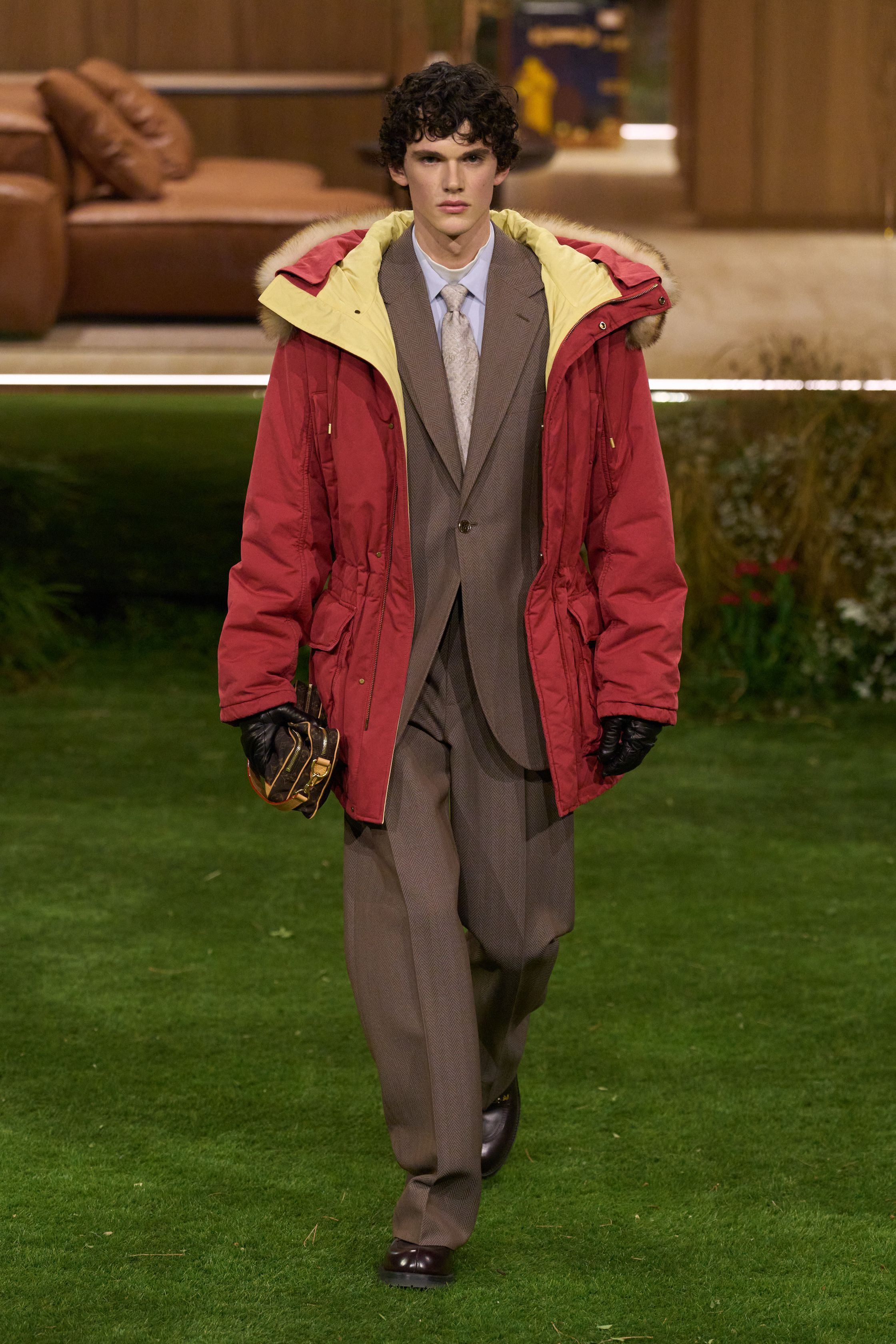 Louis Vuitton 26FW 男装以“当代绅士的旅行状态”为核心，在花园式场景中展开一场关于移动、身份与功能的叙事。功能夹克、细致西装、学院感针织与标志性包袋并行出现，色彩回归卡其、橄榄绿、灰褐与深红，呈现出低调却高度可穿的奢华现实主义。系列强化了“穿着中的生活感”，将品牌传统的旅行基因转译为更克制、更日常的现代衣橱方案-顽石频道趋势研究